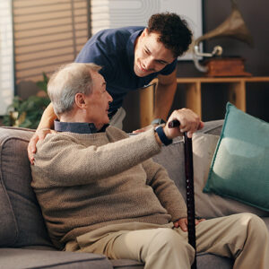 OT talking to a man sitting on a couch holding a cane