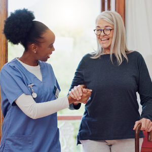 Healthcare professional helping a woman with a cane with walking