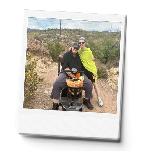 Man on a scooter with a woman standing next to him on a hiking trail in AZ